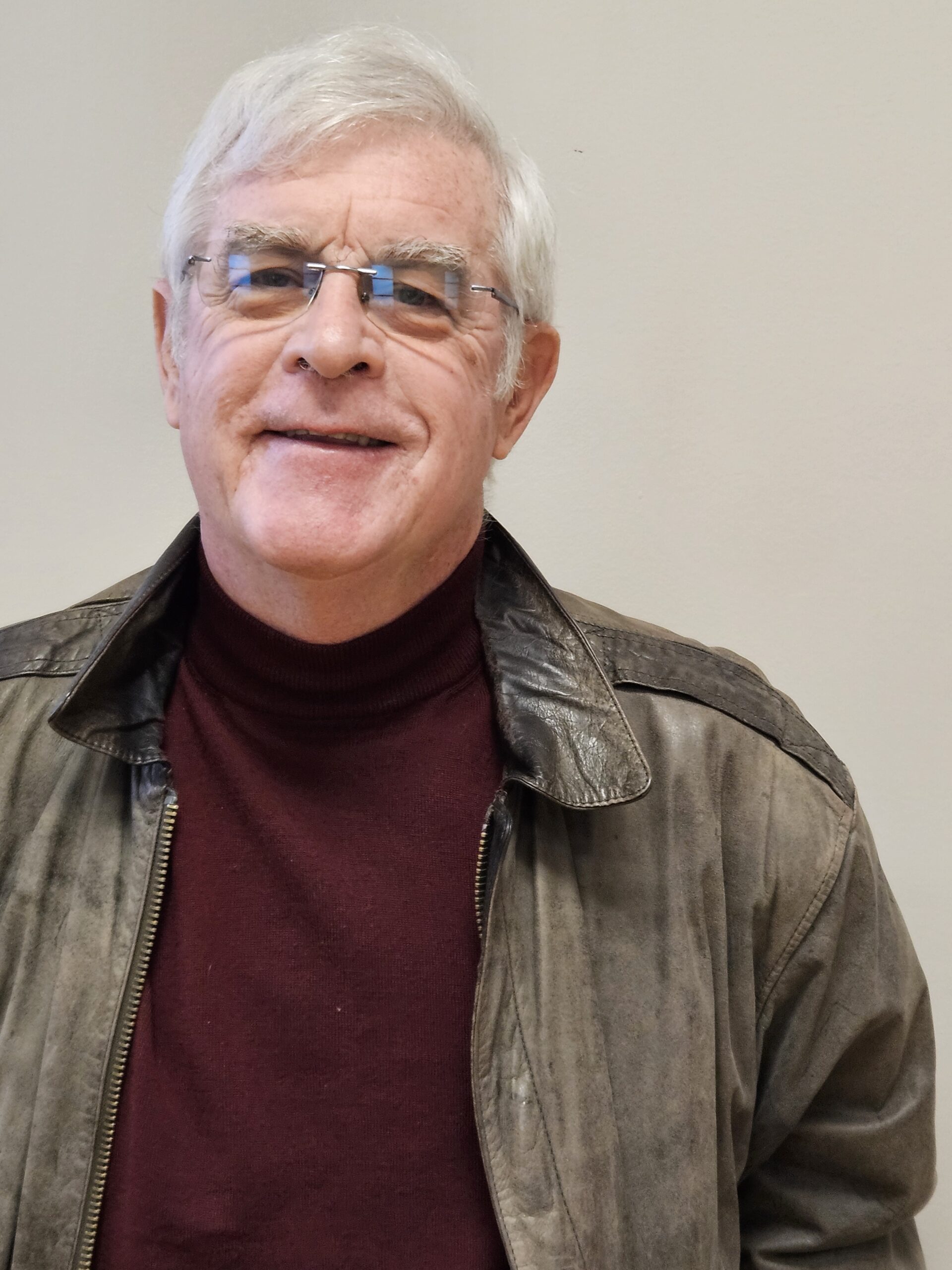 A man with glasses and a gray jacket.
