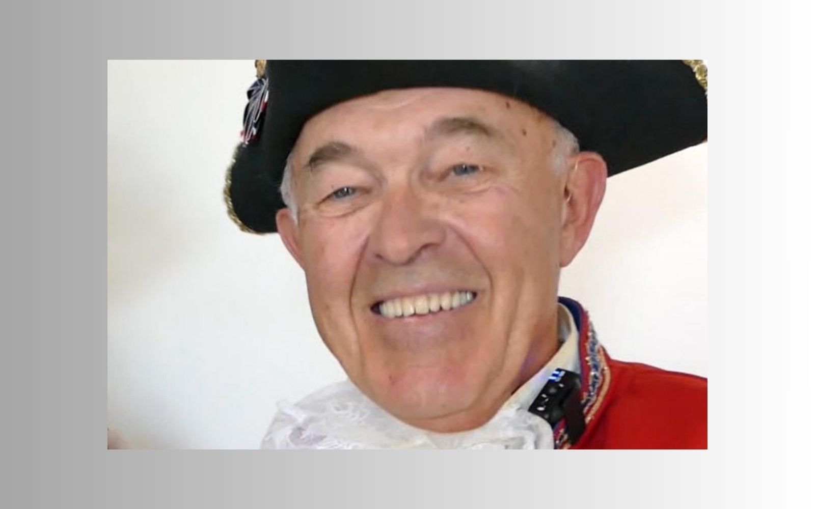 A man in a hat and red jacket smiling.